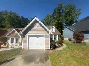 Freshly washed home exterior and driveway with clean, streak-free windows and removed screens set aside during the service